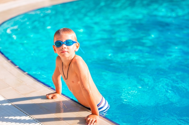 Netter glücklicher kleiner Junge in Schutzbrillen, der im Swimmingpool schwimmt und schnorchelt. Schwimmen für Kinderkonzept