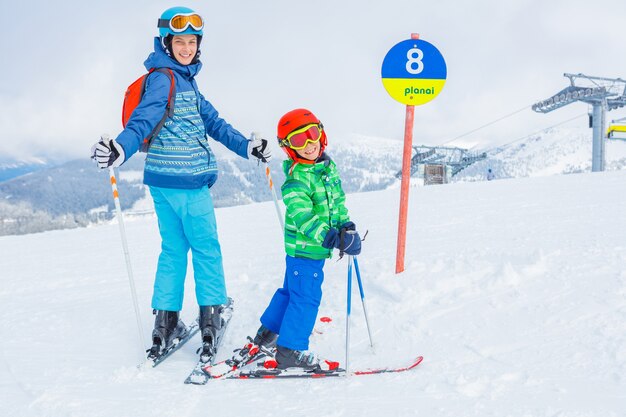 Netter glücklicher Skifahrerjunge mit seiner Schwester in einem Winterskiort.