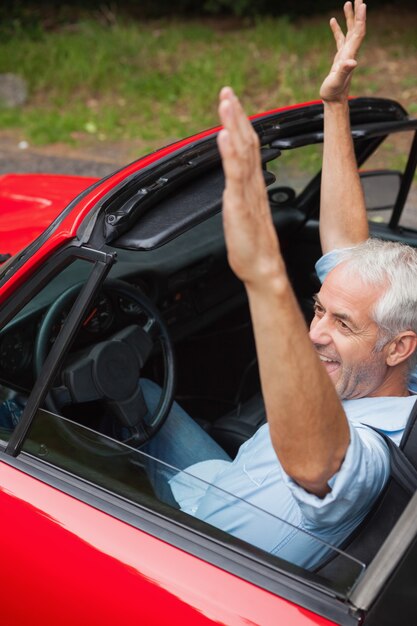 Netter gutaussehender Mann, der seinen roten Cabriolet genießt