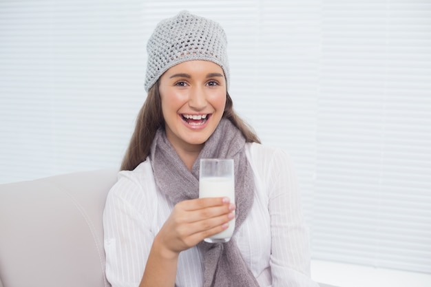 Netter hübscher Brunette mit Winterhut auf dem Halten des Glases Milch