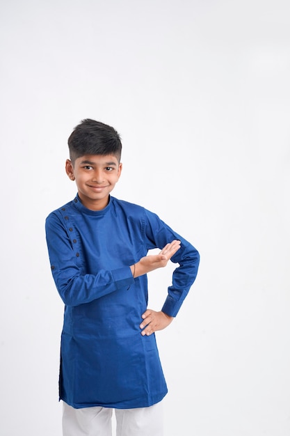 Netter indischer kleiner Junge in ethnischer Abnutzung und Ausdruck über weißem Hintergrund zeigend