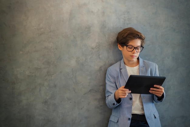 Netter jugendlich Junge mit Tablette durch Wand