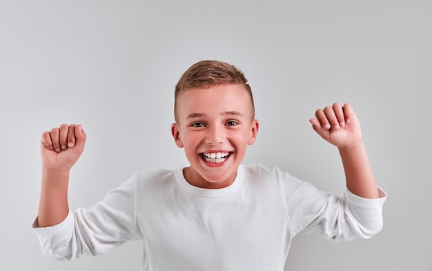 Foto netter junge auf grauem hintergrund hob seine hände und sagte ja, gewinner, viel glück.