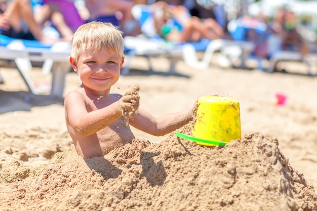 Netter Junge begraben im Sand am Meeresstrand