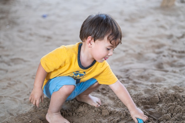 Netter Junge, der allein am Spielplatz spielt und eine glückliche Zeit hat