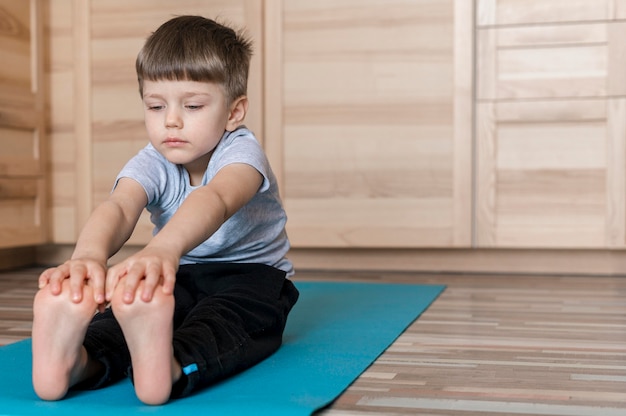 Foto netter junge, der auf yogamatte ausübt