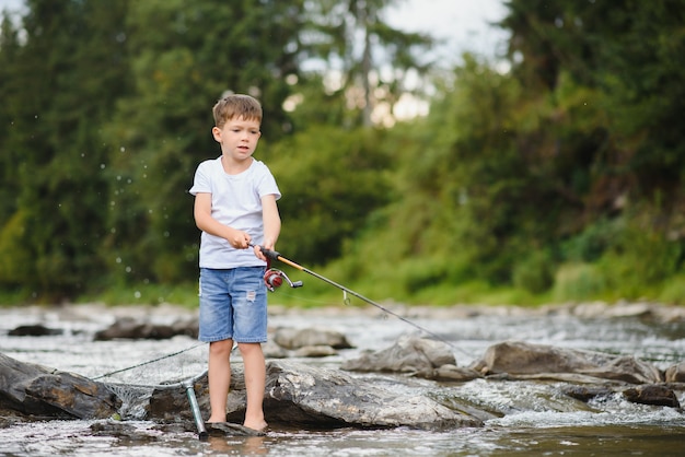 Foto netter junge, der im fluss fischt