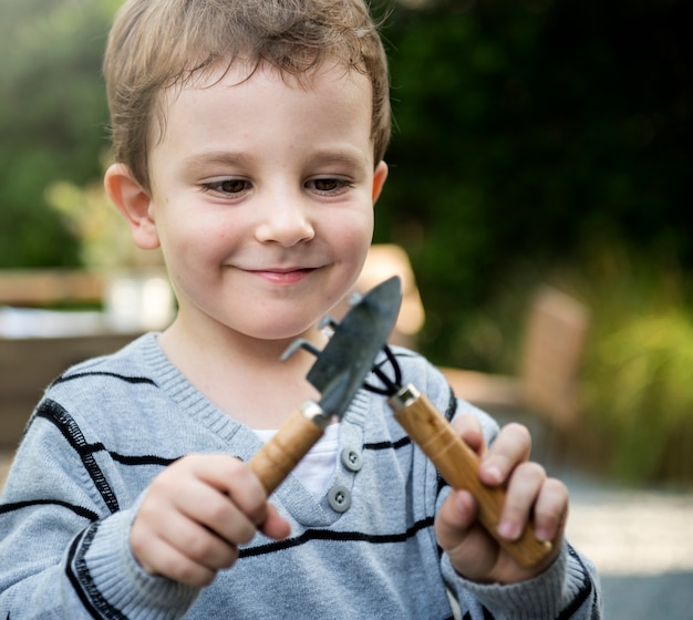 Netter Junge, der mit Gartenarbeitwerkzeugen spielt