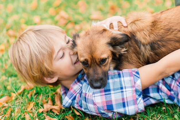 Netter Junge, der mit seinem Hund auf der Wiese spielt und geht.