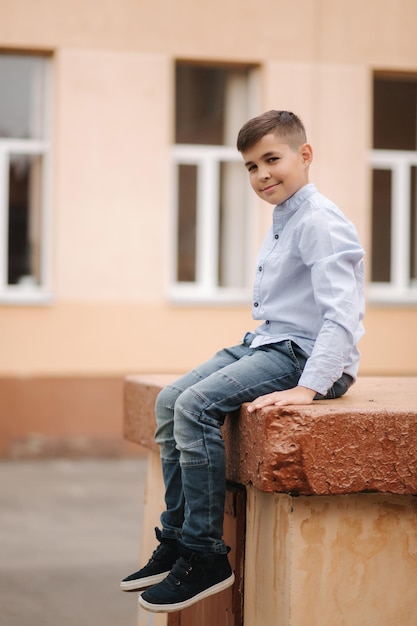 Netter Junge im Hemd steht vor der Schule