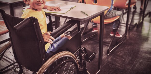 Foto netter junge im rollstuhl, der in der klasse sitzt