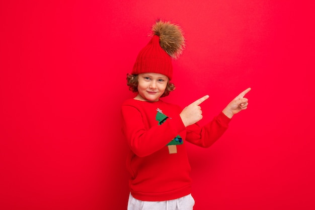 Netter Junge mit einem Weihnachtspullover und einem Hut