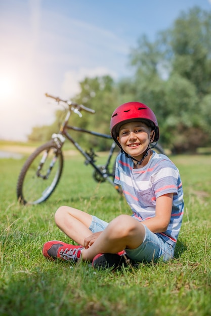 Foto netter junge mit helm neben seinem fahrrad auf dem rasen