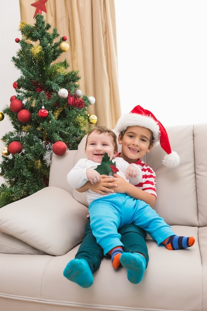 Netter Junge und Babybruder auf Couch am Weihnachten