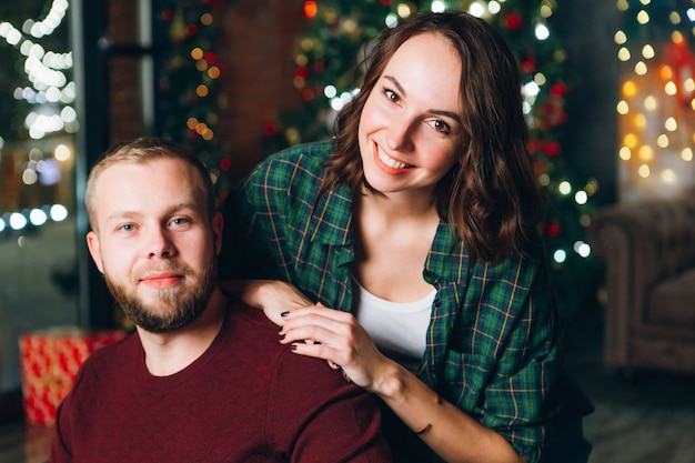 Netter junger Familienmann und Ehefrau am Weihnachtsbaum