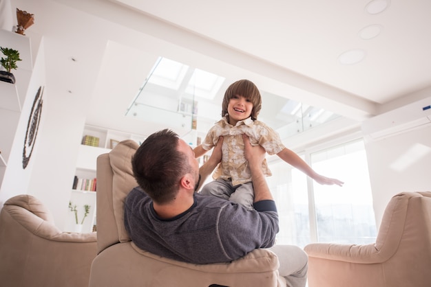 Netter junger Junge, der Spaß mit Vater auf Sofa hat