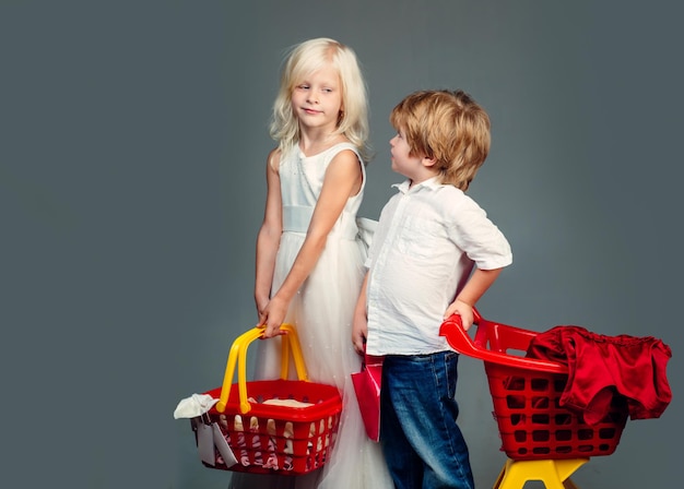 Foto netter käufer kunde kunde hält einkaufswagen mädchen und jungen kinder einkaufen paar kinder halten plastik ...