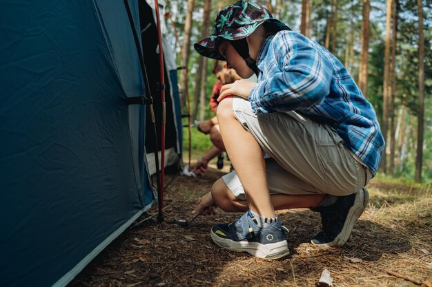 Foto netter kaukasischer junge, der ein zelt-familiencamping-konzept aufstellt