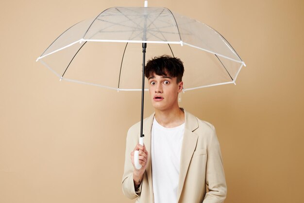 Netter Kerl in einer Jacke mit offenem Regenschirmschutz