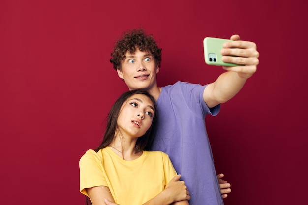 Netter Kerl und Mädchen in bunten T-Shirts mit einem Telefon isolierten Hintergrund