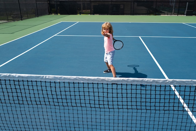 Netter Kinderjunge beim Tenniswettbewerb. Kleiner Junge, der Tennis am Hof spielt.