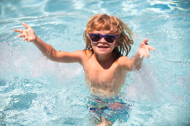 Netter kinderjunge schwimmt im schwimmbadsommerwasserhintergrund mit kopienraum süßer junge im wasserp...