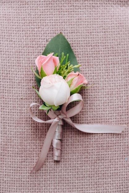 Netter klassischer Bräutigam Boutonniere, der schöne Rosen lokalisiert auf rosa strukturiertem Hintergrund kennzeichnet