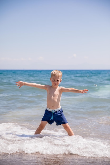 Netter kleiner Junge, der am Strand am Meer spielt, ist er glücklich Konzept Sommerurlaub Restspaß