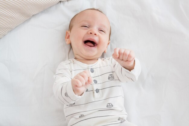 Netter kleiner Junge, der auf Bett lacht