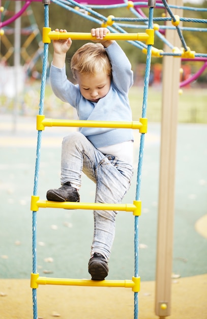 Netter kleiner Junge, der auf einer Dschungelgymnastik klettert