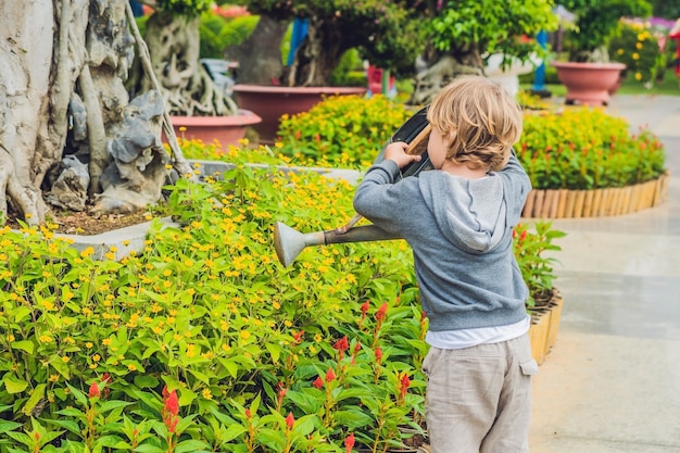 Netter kleiner Junge, der Blumen gießt, die Dose gießen