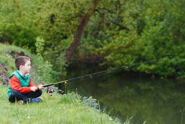 Netter kleiner Junge, der in der Natur fischt