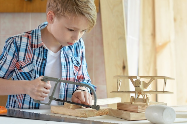 Netter kleiner Junge, der in der Werkstatt mit Holz arbeitet