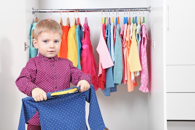 Foto netter kleiner junge, der kleidung im kleiderschrank wählt