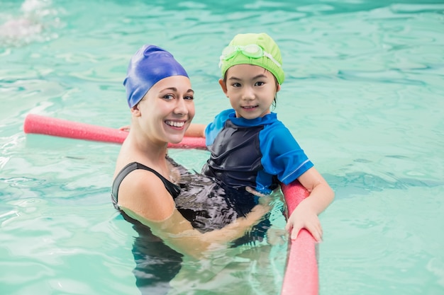 Netter kleiner Junge, der lernt, mit Trainer zu schwimmen