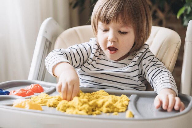 Netter kleiner Junge, der mit kinetischem Sand spielt Entwicklung der Feinmotorik Frühe sensorische Erziehung Aktivitäten Montessori Sensorische Spiele zu Hause