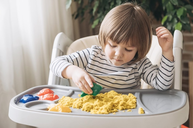 Netter kleiner Junge, der mit kinetischem Sand spielt Entwicklung der Feinmotorik Frühe sensorische Erziehung Aktivitäten Montessori Sensorische Spiele zu Hause