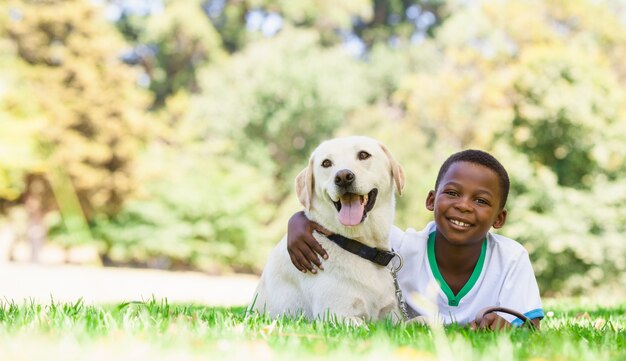 Netter kleiner Junge, der mit Labrador-Hund liegt