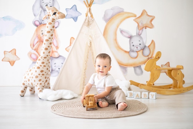 Netter kleiner Junge, der mit natürlichem Holzspielzeug im Kinderzimmer zu Hause spielt Lernspielzeug für Kinder