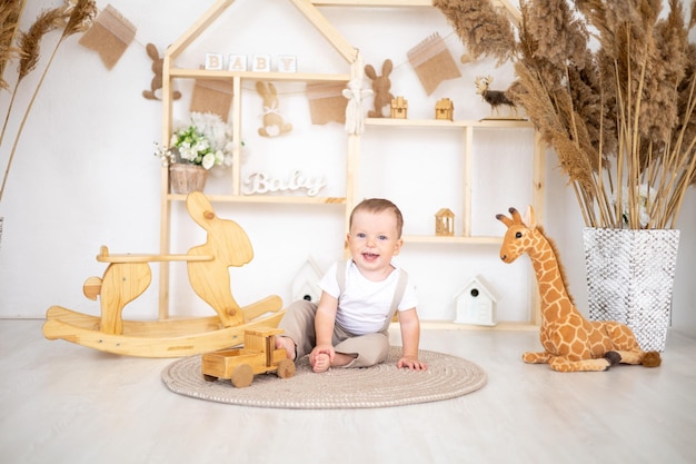 Netter kleiner Junge, der mit natürlichem Holzspielzeug im Kinderzimmer zu Hause spielt Lernspielzeug für Kinder