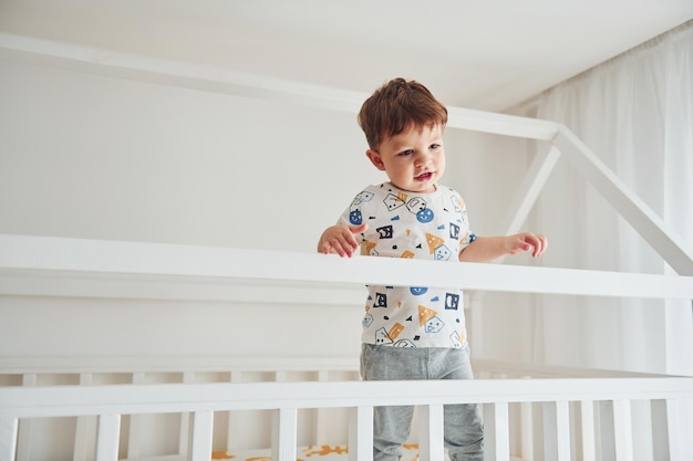 Netter kleiner Junge, der sich ausruht und drinnen im Schlafzimmer Spaß hat