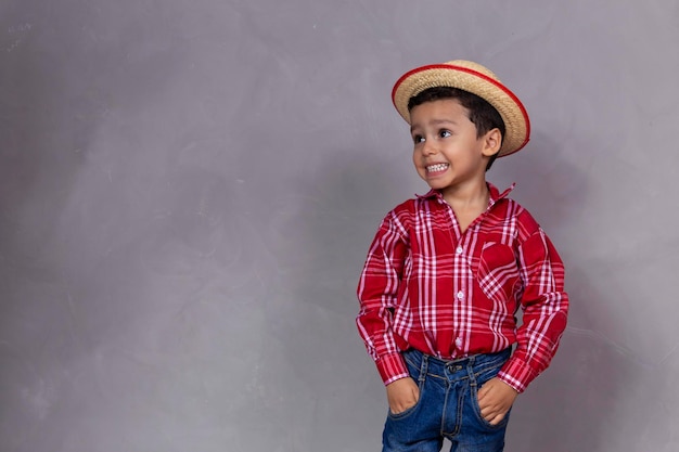 Netter kleiner Junge, der typische Kleidung für Festa Junina mit Kopienraum trägt