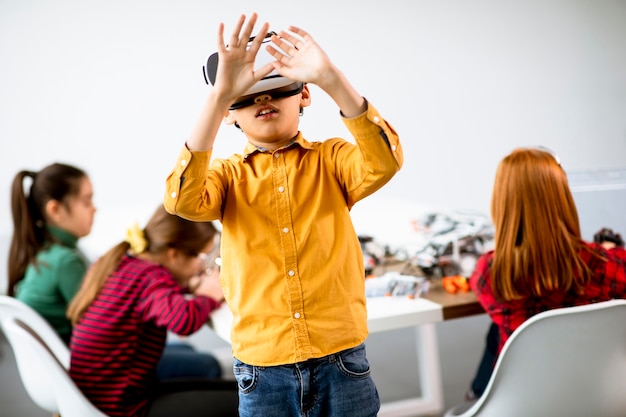 Netter kleiner Junge, der VR-Virtual-Reality-Brille in einem Robotik-Klassenzimmer trägt