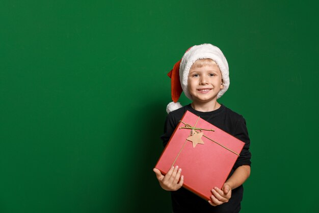 Netter kleiner Junge im Weihnachtsmannhut und mit Weihnachtsgeschenk