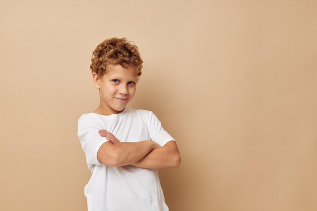 Netter kleiner Junge in einem weißen T-Shirt, das den unveränderten Spaß-Lebensstil aufwirft