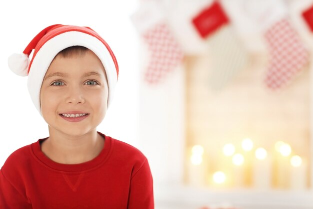 Netter kleiner Junge in Weihnachtsmütze auf verschwommener Oberfläche