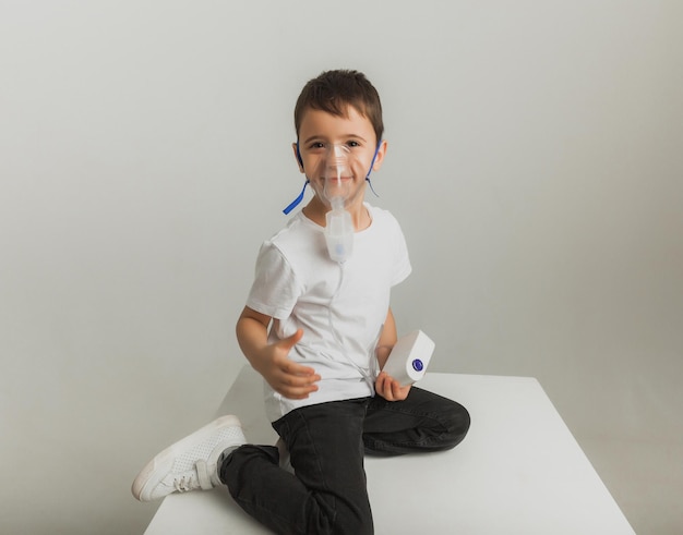 Netter kleiner Junge macht Einatmen. Das Kind hält einen Inhalator in der Hand und wird gegen Husten behandelt. hochwertiges Studiofoto.