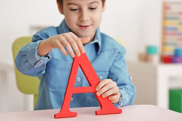 Netter kleiner Junge mit Buchstabe A im Büro des Logopäden