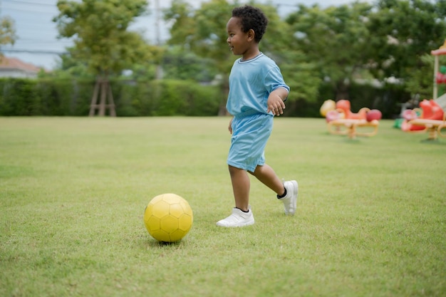 Netter kleiner Junge mit Fußball im Park an einem sonnigen Tag
