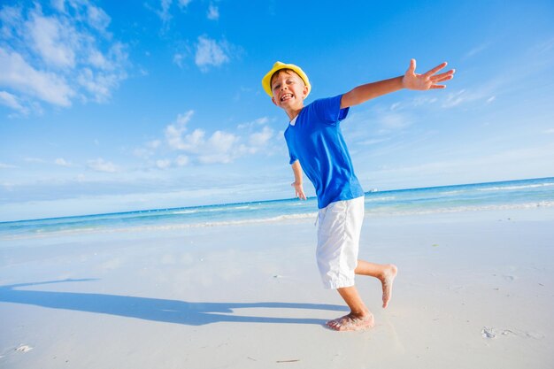 Netter kleiner Junge mit gelbem Hut, der sich am Meeresstrand amüsiert